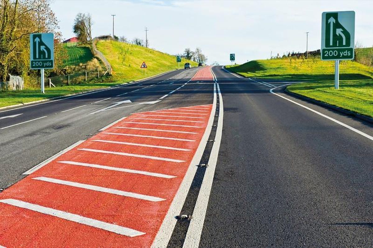 Red high-friction anti-skid surfacing with white hatching on a road approach