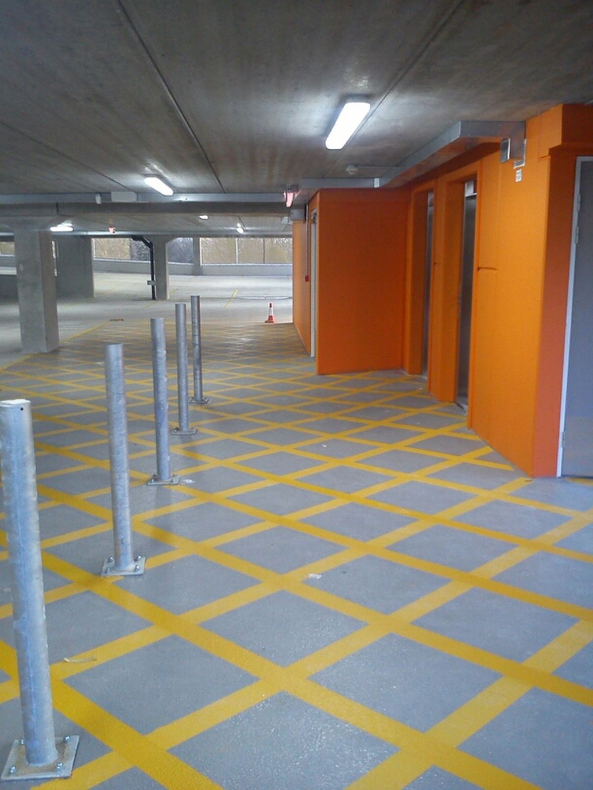 Underground multi-storey car park with orange lift lobby walls and fresh bay markings