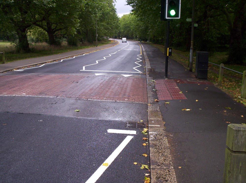 Freshly applied white zig-zag road markings on new asphalt