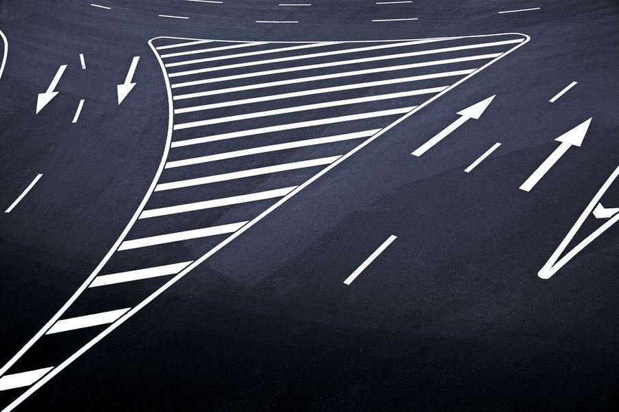 Close-up of white chevron road markings on dark asphalt